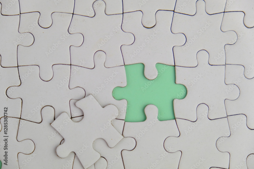 white jigsaw puzzle with missing puzzle for a text template. Above photo of isolated on the green background white jigsaw puzzle with missing puzzle for a text template. Above photo of isolated on the green background