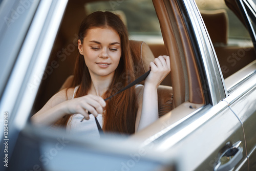 A young woman fastening her seatbelt in a car, showcasing a safe driving concept with a cheerful expression and a warm background. photo