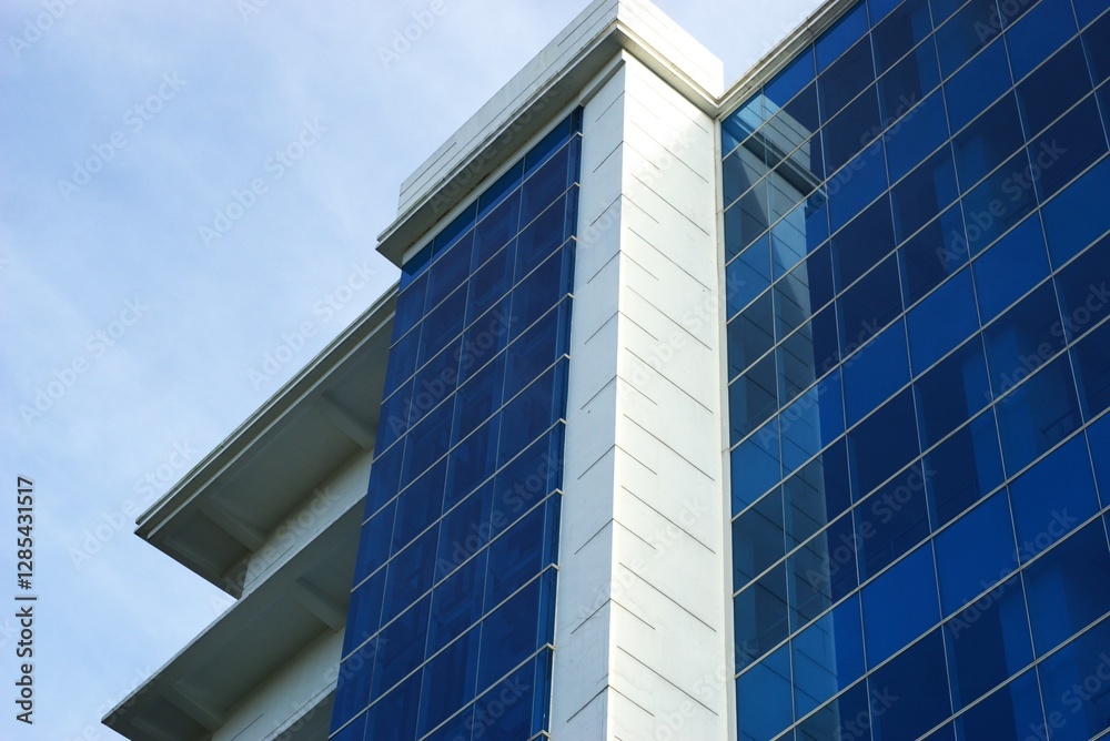 low angle of modern office building with blue glass window facade and white wall low angle of modern office building with blue glass window facade and white wall