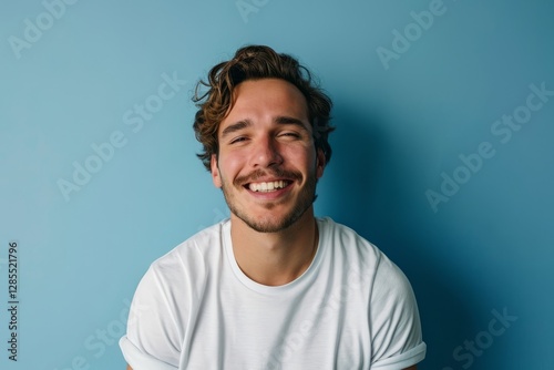 Close up portrait of a smiling young man in a white t-shirt on a blue background
