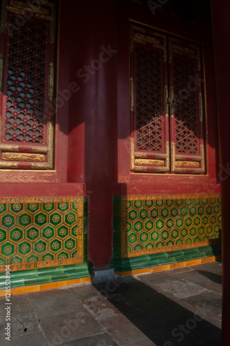 Beautiful roof terrace shadow over decorated red wall and vintage wooden windows in Forbidden City Complex in Beijing, China.