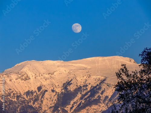 The moon above a foothill of the Monte Baldo mountain range on Lake Garda.