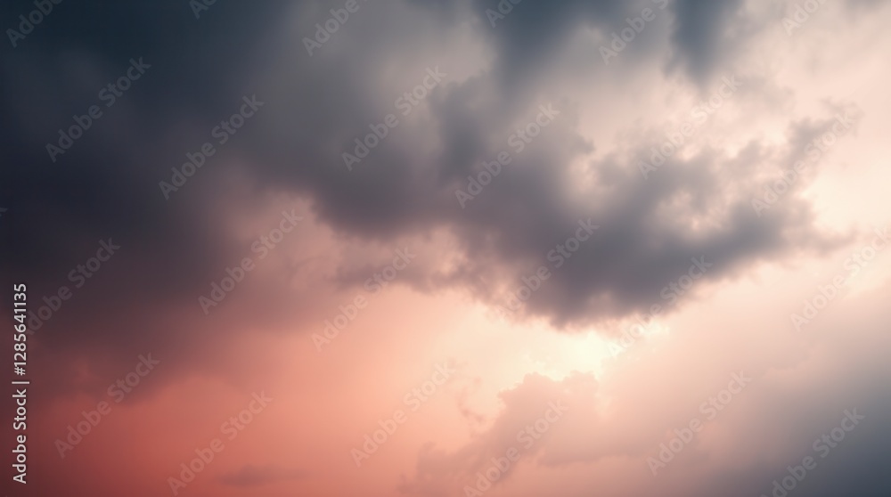 Obraz premium A dramatic cloudscape at sunset with dark storm clouds illuminated by a soft, ethereal pink light.
