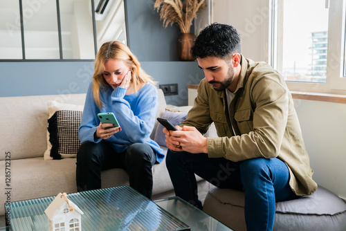 Fotografie Two young adults engaged in focused smartphone usage while sitting comfortably o