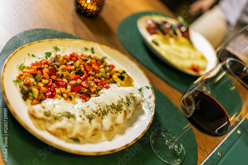 Delicious plate seved in restaurant. Meat in white sauce with vegetables and red wine. photo