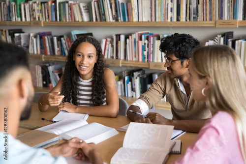 Group of multinational high school or university students engaged in exam preparation, sharing ideas, testing each other, studying together met in library, focus on African girl explain point of view