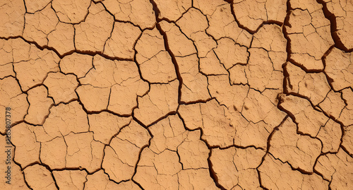 Cracked dry clay texture background. Deep fissures in sun-baked earth, earthy brown tones