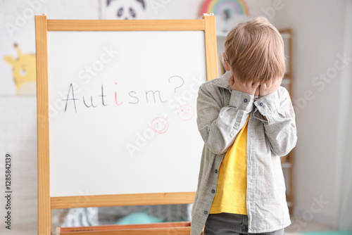 Stressed little boy and board at psychologist's office. World Autism Awarenes...