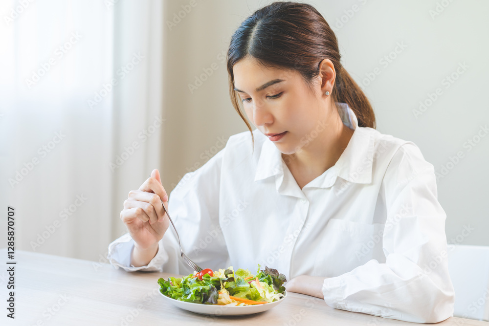 Diet in bored face, unhappy beautiful asian young woman, girl on dieting, holding fork at tomato on salad plate, dislike or tired with eat fresh vegetables. Nutrition of clean, healthy food good taste Diet in bored face, unhappy beautiful asian young woman, girl on dieting, holding fork at tomato on salad plate, dislike or tired with eat fresh vegetables. Nutrition of clean, healthy food good taste