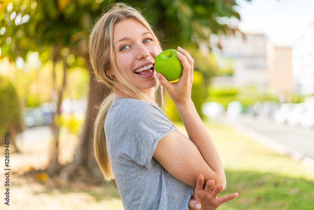 Young blonde woman at outdoors eating an apple Young blonde woman at outdoors eating an apple