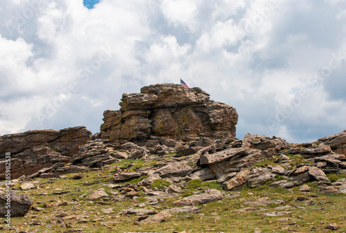 Summit View Featuring a Flag Atop a Rock Formation Under a Cloudy Sky in Rocky Mountain National PArk