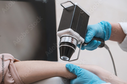 Closeup  doctor examines neoplasms or moles on the woman hand patient's skin - using special apparatus for dermatoscopy digital dermoscope. Prevention of melanoma and skin cancer. World Cancer Day
