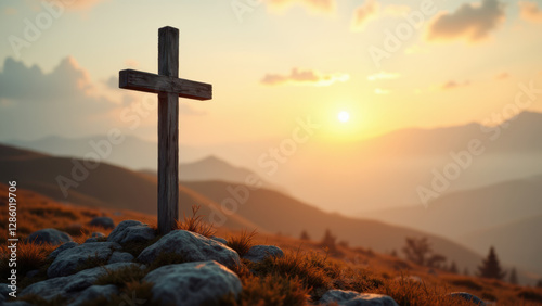 A cross stands on a rocky hillside with mountains in the background at sunrise or sunset.