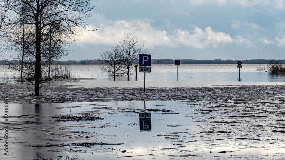 latvian winter landscape with flooded lake, thin and light ice in places, reflections