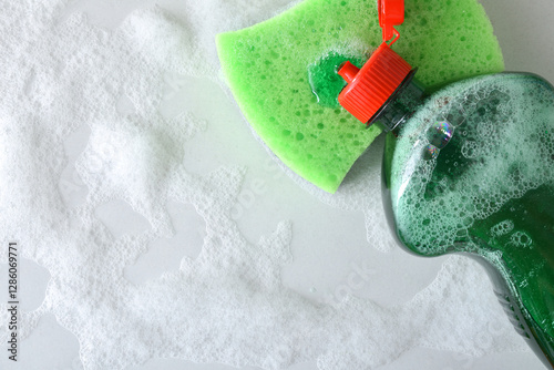 Open detergent bottle spilling detergent onto a green scouring pad