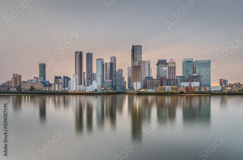 Canary Wharf shot from the Greenwich peninsula at slack tide in the golden hour, creating a lovely reflection in the water and a pastel coloured sky.