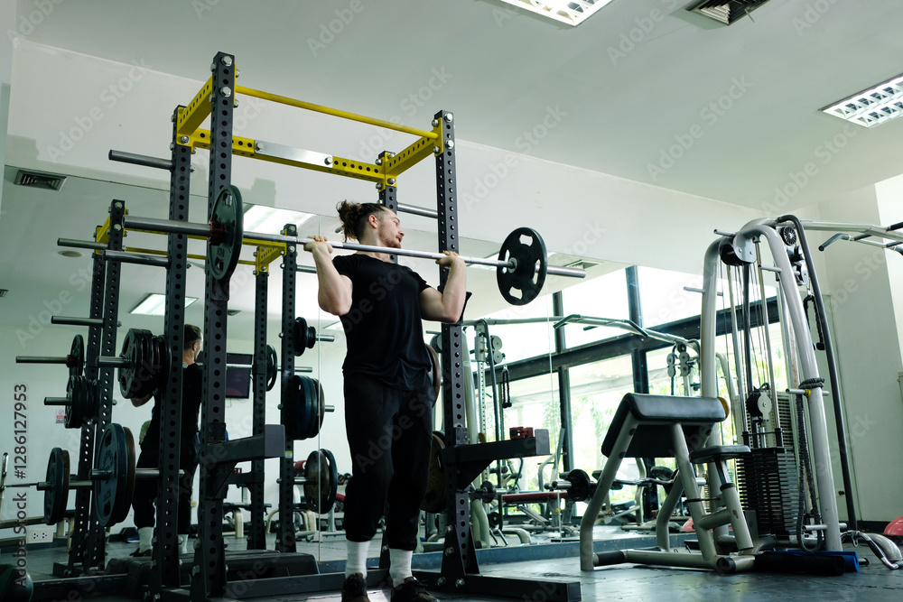 Fototapeta premium Young man using weight lifting exercise in fitness gym. Fitness concept.