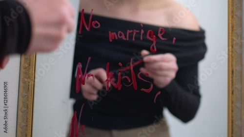 Woman writing ‘No marriage, no kids, no pressure’ on mirror with red lipstick.