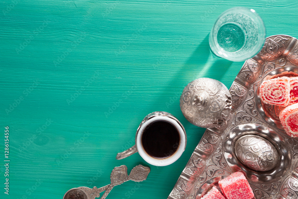 Traditional Turkish coffee, Turkish delight and a glass of water on a wooden table painted in mint-green. Top view
