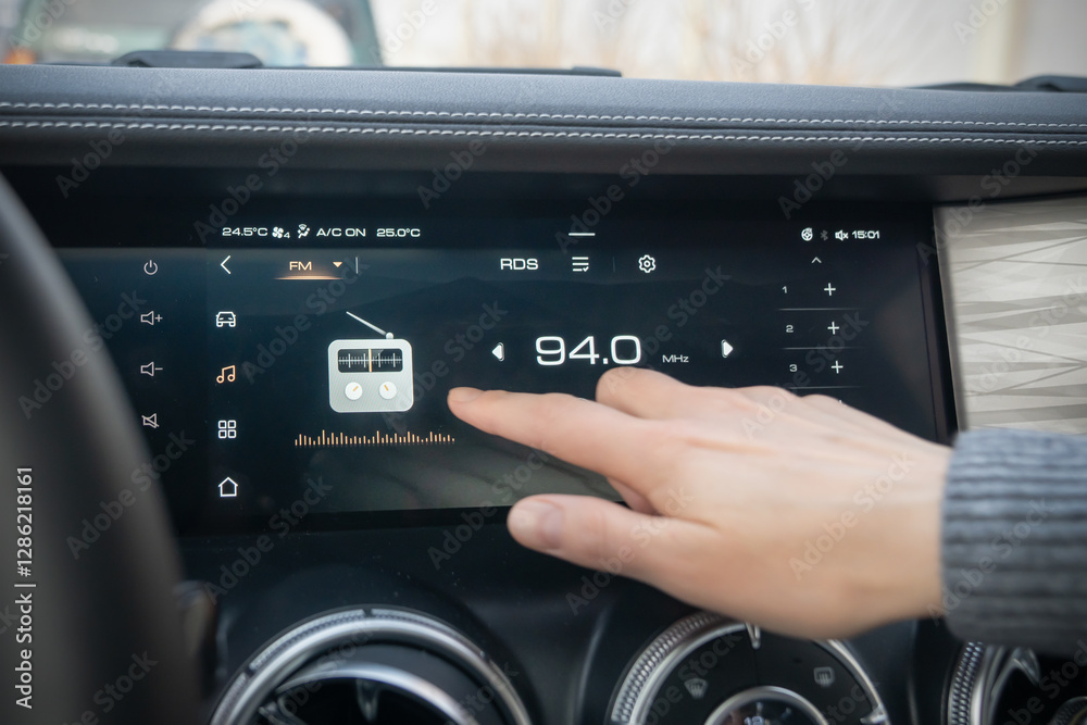 Fototapeta premium A detailed closeup view of a cars touchscreen dashboard displaying radio tuning and an engaging user interaction. Setting up the radio and media system on the touchpad with your hand and finger on the