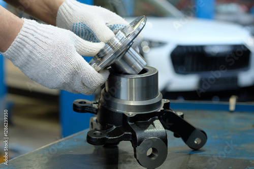 Car suspension repair. An auto mechanic prepares the front wheel hub for replacement and the installation of a new front hub bearing.The right rotary lever. Inspection and control of spare parts.