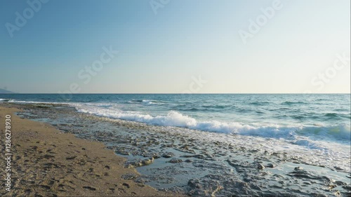 A captivating slow motion still shot of ocean waves crashing against rugged coastal rocks during the daytime