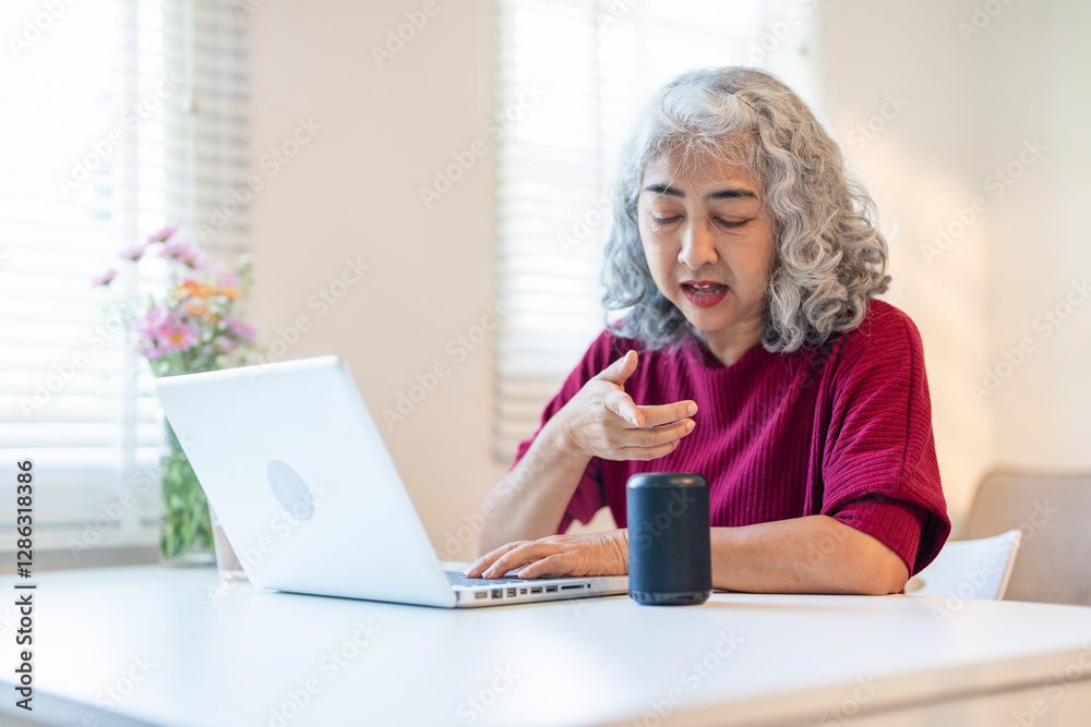 Modern granny smiling and saying with smart speaker in cozy apartment living room controls the speaker using voice commands. Modern granny smiling and saying with smart speaker in cozy apartment living room controls the speaker using voice commands.