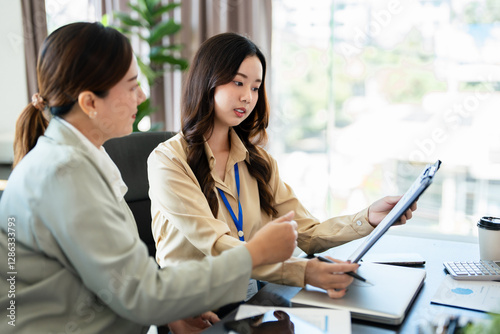 Female senior and junior managers sitting at desk working together in a business team