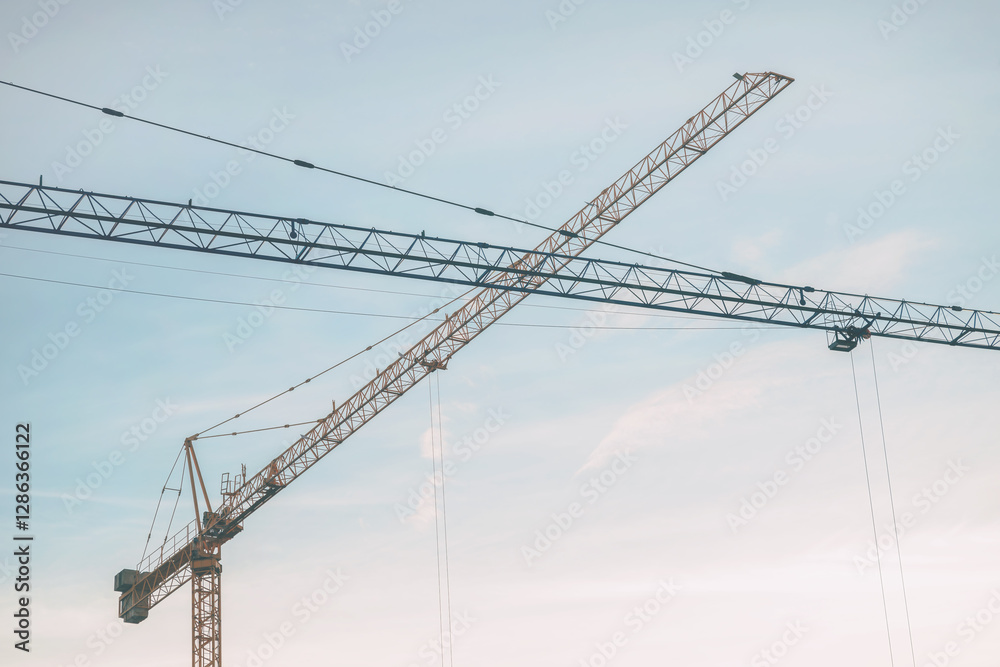 Construction cranes lifting heavy load on construction site Construction cranes lifting heavy load on construction site