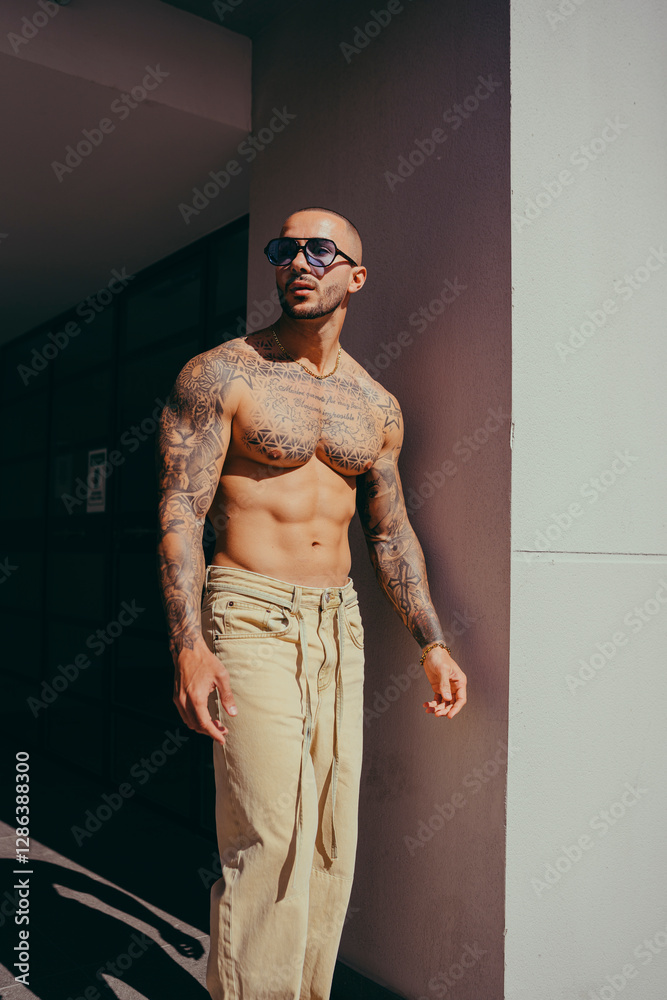 Chico joven tatuado posando con ropa actual en la calle