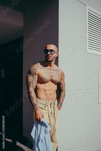 Obraz na płótnie Chico joven tatuado posando con ropa actual en la calle w salonie