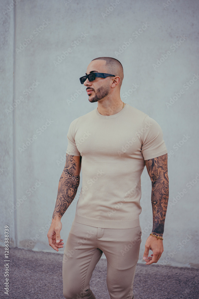 Chico joven tatuado posando con ropa actual en la calle