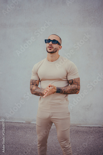 Obraz na płótnie Chico joven tatuado posando con ropa actual en la calle w salonie