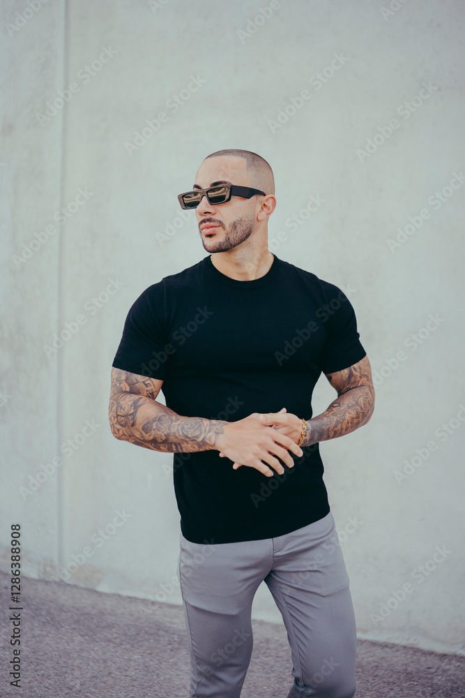 Chico joven tatuado posando con ropa actual en la calle