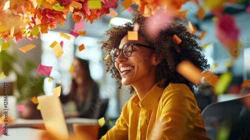 Smiling Woman with Glasses Surrounded by Colorful Confetti in a Creative Office Environment