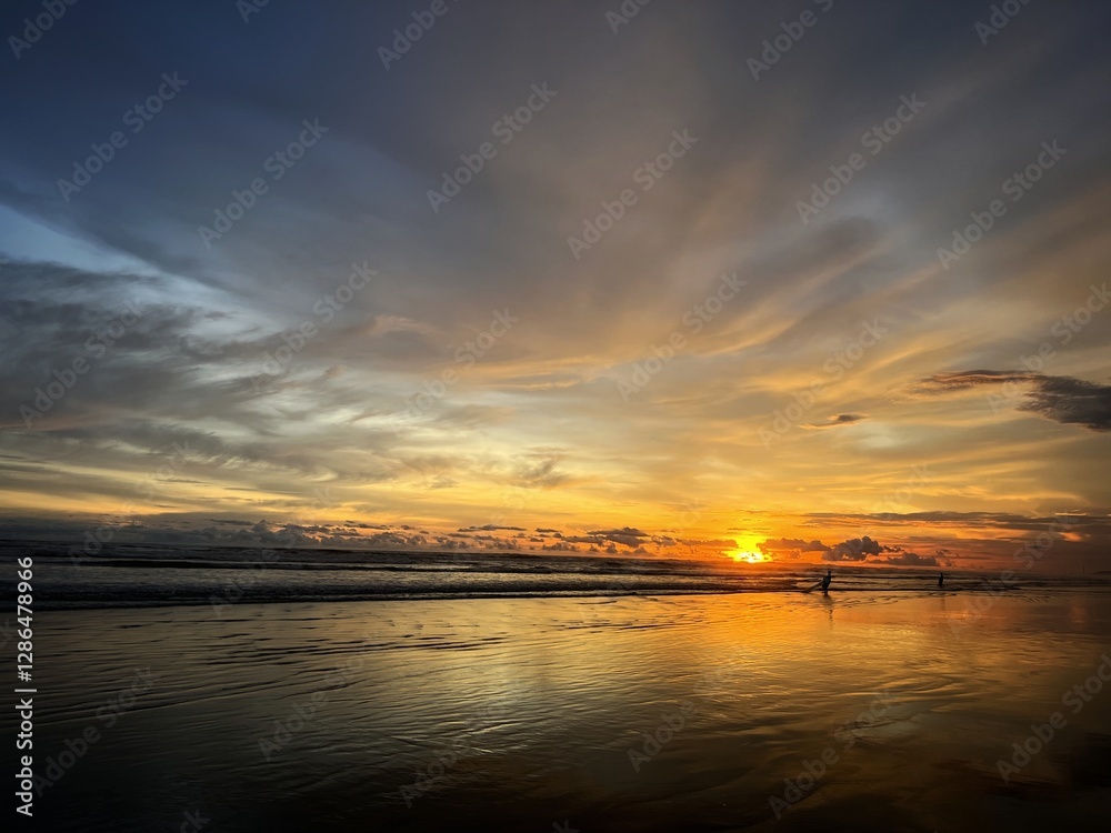 Obraz premium The natural beauty of the sunset on the beach, and the activity of fishermen looking for fish can be seen.