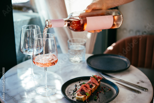 Obraz na płótnie Pouring rose wine at a dinner party with friends in a bar or restaurant. w salonie