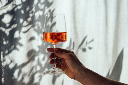 Obraz na płótnie Hand holding a glass of rose wine in summer sunshine during a wine tasting in a bar or restaurant. w salonie