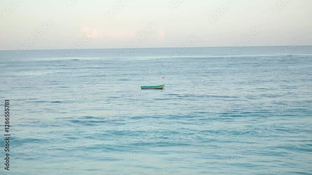 A boat moored in the middle of the sea, under the sunset A boat moored in the middle of the sea, under the sunset
