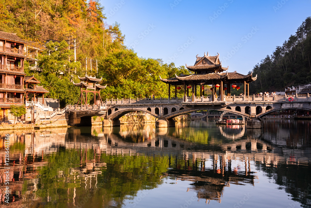 Old bridge in Fenghuang ancient town, China. Traditional chinese wooden houses in old watertown Old bridge in Fenghuang ancient town, China. Traditional chinese wooden houses in old watertown