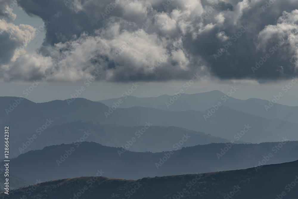 mountain ranges stretch to the very horizon like waves, low, heavy gray clouds above them mountain ranges stretch to the very horizon like waves, low, heavy gray clouds above them