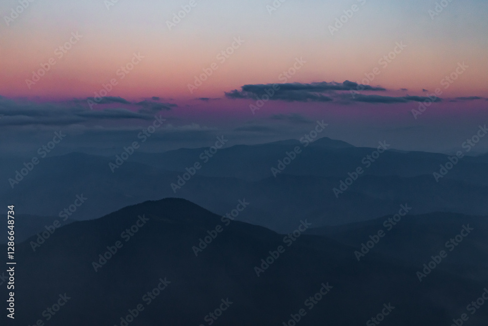 Obraz premium dark silhouettes of mountain peaks against a purple sky after sunset