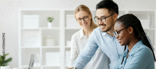 Three people are sitting at a desk with a laptop in front of them