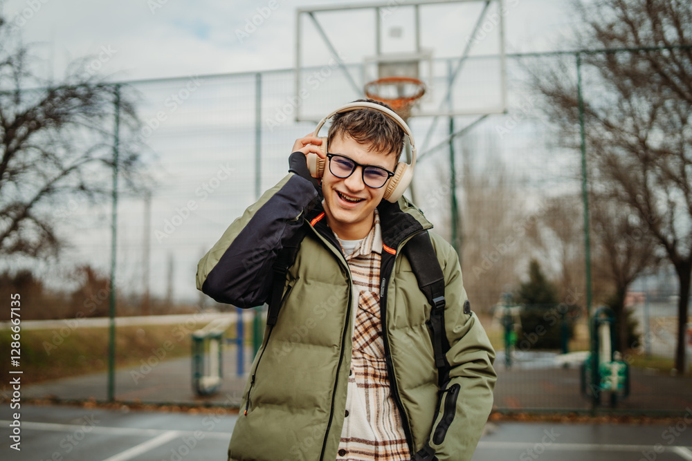 Fototapeta premium Portrait of a young smiling man wear headphones on basketball court 