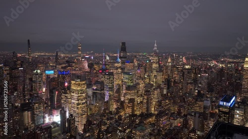 Nighttime cityscape illumination sweeping across Manhattan skyline, revealing architectural complexity from high altitude aerial view capturing urban energy photo