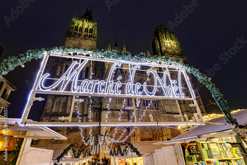 ROUEN, NORMANDY, FRANCE - 2025: entrance to Christmas Market, chalets with delicatessen shops, illuminated Notre Dame Cathedral, cobbled pedestrian street in historic center