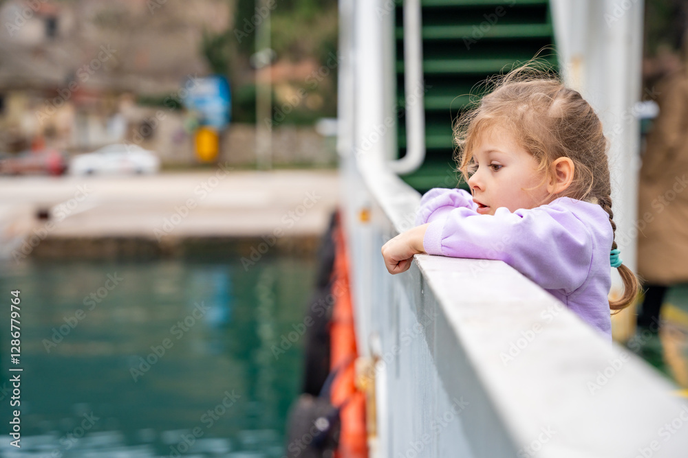 Little girl traveling with family by ferry. Crossing from one bank to another of Kotor bay in Montenegro