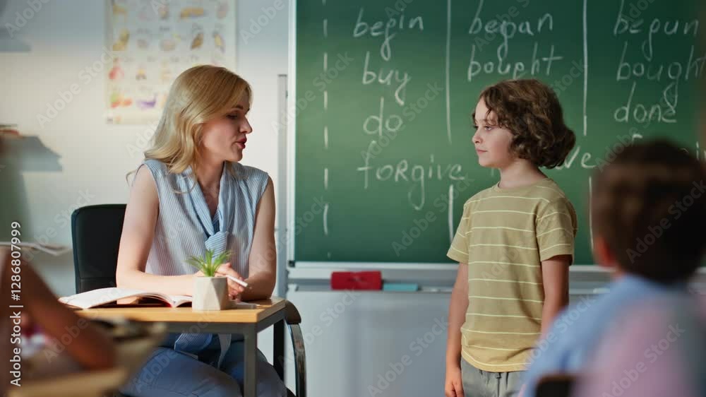 School educator asking boy at lesson. Cute schoolboy answering homework in class School educator asking boy at lesson. Cute schoolboy answering homework in class