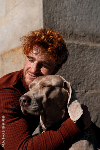 Young ginger haired boy hugging his dog with eyes closed cute love scene with pets