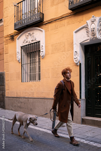 Young ginger haired boy and his dog and walking through yellow European streets